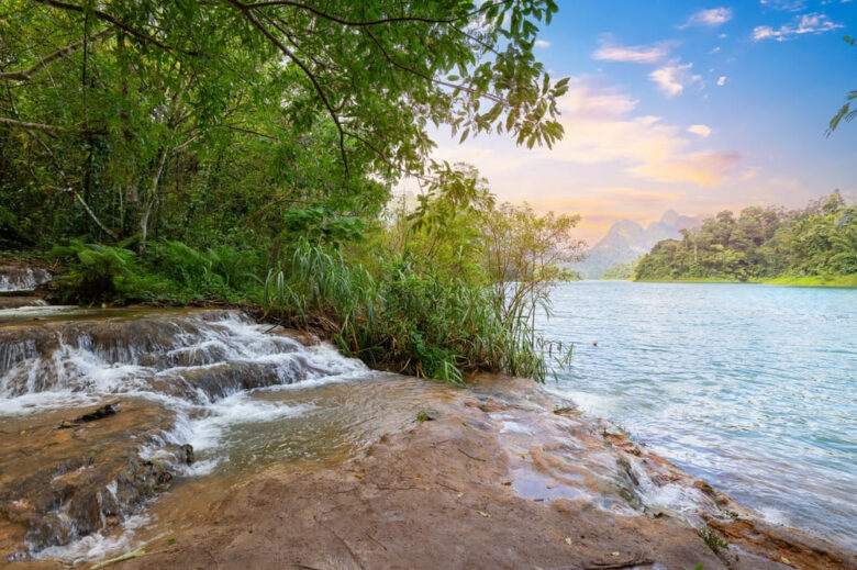 Small cascade flowing into Cheow Lan Lake at sunset, a scenic waterfall in Khao Sok to explore